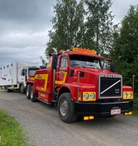 Hinauspalvelu Kuljetus Saintula Ky:n raskaankaluston hinausauto "Niilo", joka hinaa perässään valkoista kuorma-autoa.